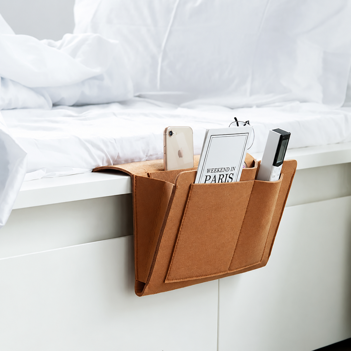 Orange hängande sängförvaring med telefon, bok och småföremål